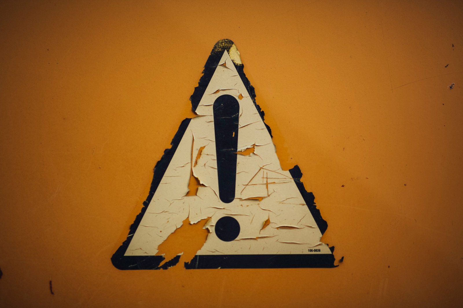 a triangle shaped sign on a yellow wall